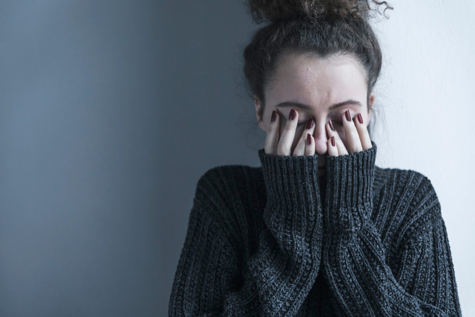 depresivna devojka  u džemperu sa rukama na očima