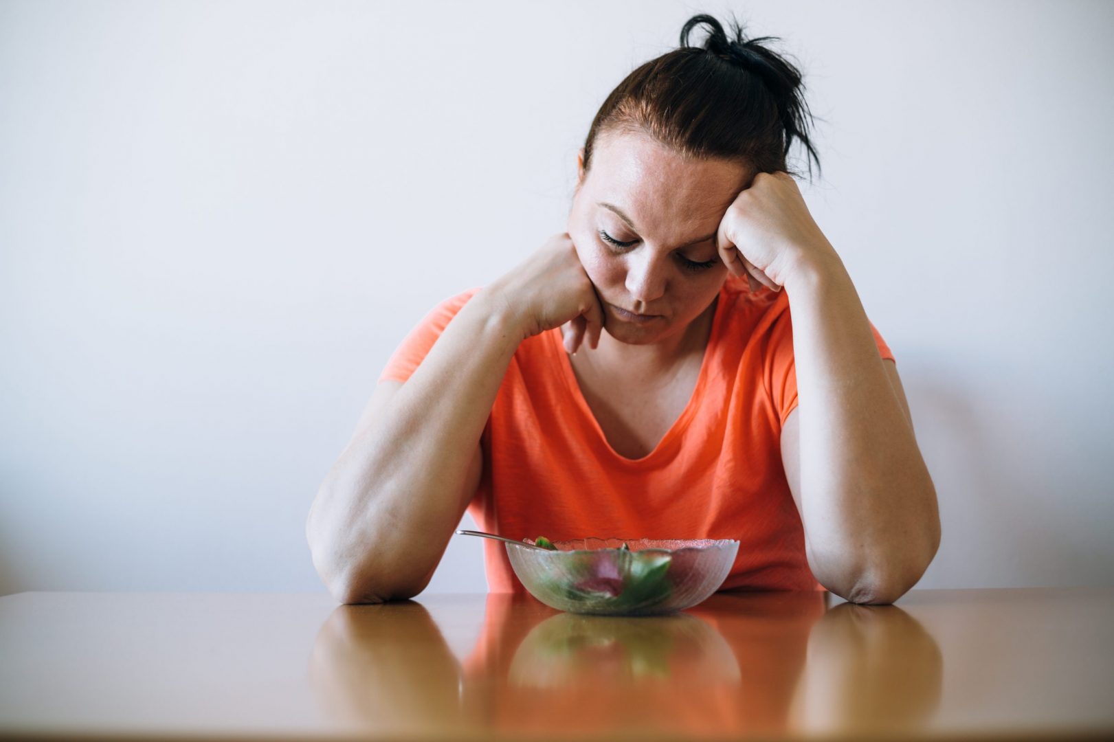 depresivna žena gleda u tanjir