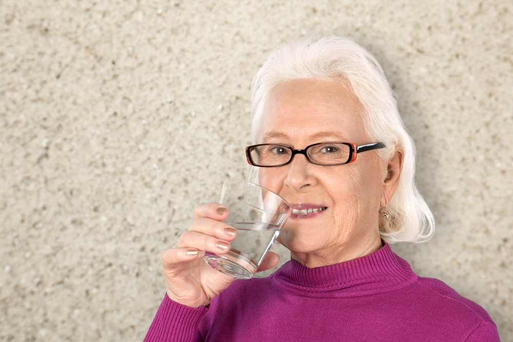 starija žena pije vodu