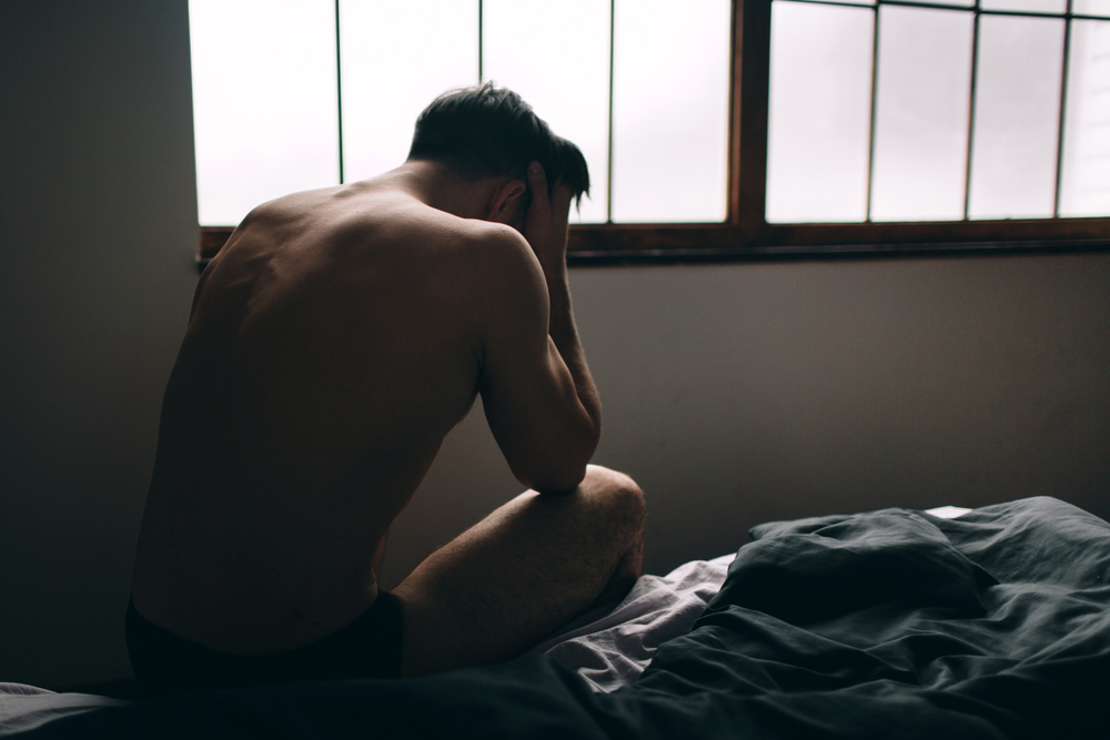 depresivan muškarac sedi na krevetu