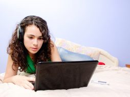 tinejdžerka za računarom na krevetu